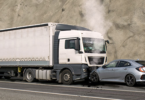 A large semi-truck and a small sedan are involved in a head-on collision on a highway.