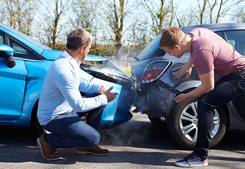Two men assessing the damage to their cars after a fender-bender.